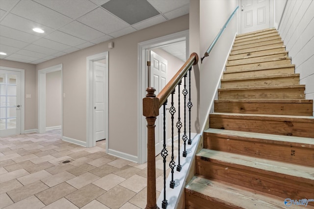 staircase featuring recessed lighting, baseboards, and a drop ceiling