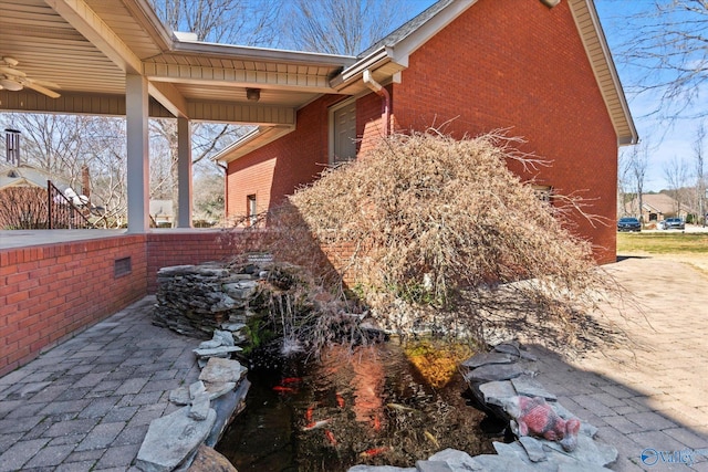 view of side of home with brick siding and a ceiling fan