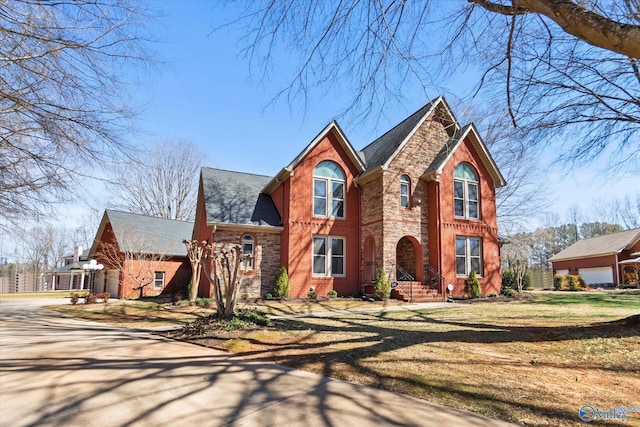view of front of property featuring stone siding, brick siding, a front lawn, and a shingled roof