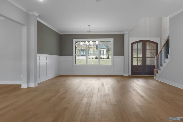 unfurnished dining area with hardwood / wood-style floors, crown molding, french doors, and a chandelier