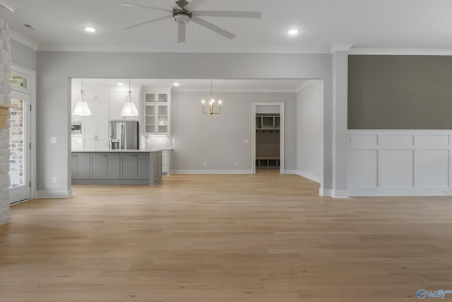 unfurnished living room featuring ornamental molding, ceiling fan with notable chandelier, and light hardwood / wood-style flooring