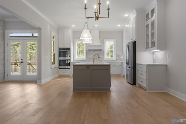 kitchen with a kitchen island with sink, pendant lighting, white cabinets, and appliances with stainless steel finishes