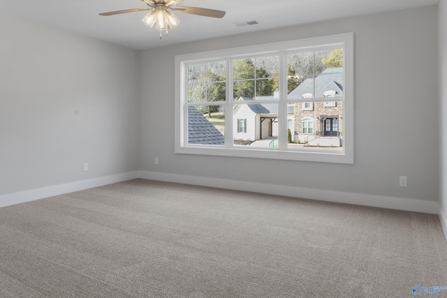 carpeted empty room with ceiling fan and plenty of natural light