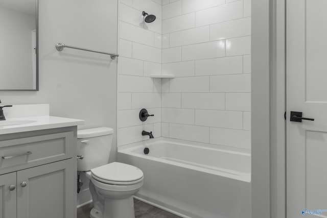 full bathroom featuring vanity, tiled shower / bath, and toilet