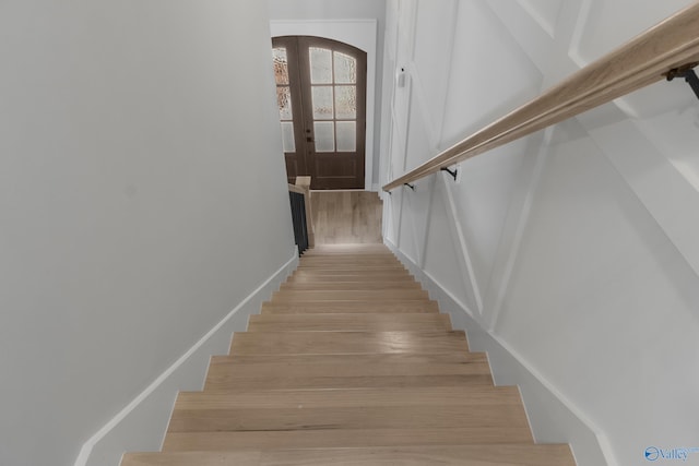 stairs featuring french doors and hardwood / wood-style floors