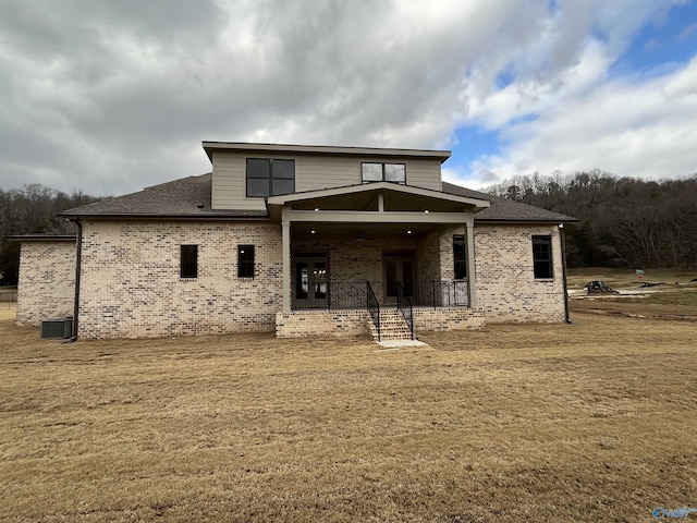 rear view of property featuring central AC and a lawn