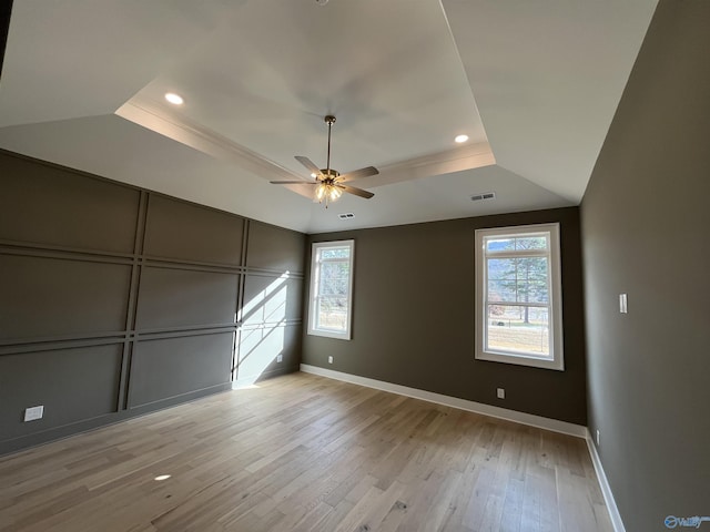 unfurnished bedroom featuring a raised ceiling, ceiling fan, and light hardwood / wood-style flooring