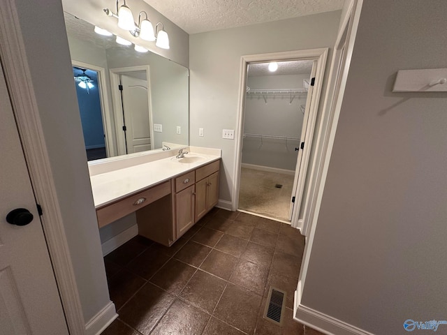 bathroom featuring vanity, ceiling fan, and a textured ceiling