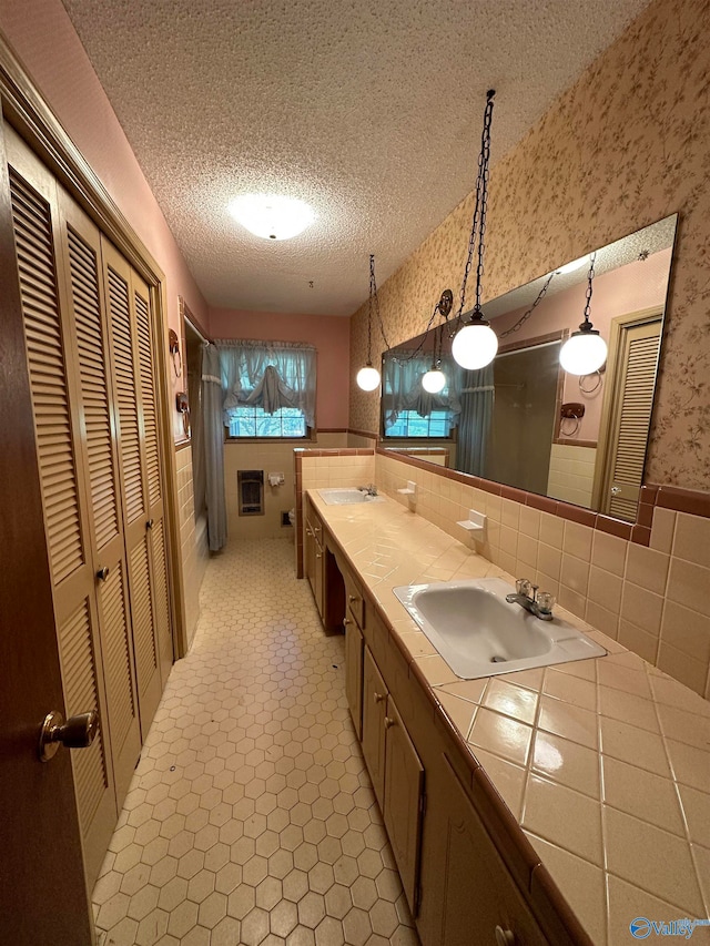 bathroom with tile patterned floors, tasteful backsplash, vanity, and a textured ceiling