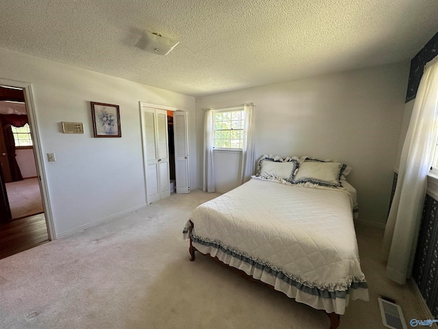 bedroom featuring a closet, a textured ceiling, and light colored carpet