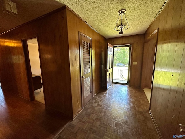 doorway with a textured ceiling, wooden walls, and dark parquet floors