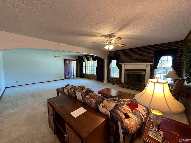 carpeted living room featuring a brick fireplace, brick wall, a wealth of natural light, and ceiling fan