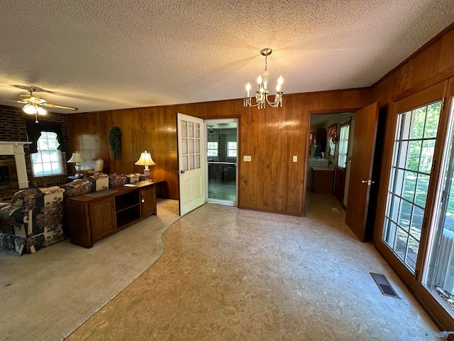 kitchen featuring a textured ceiling, ceiling fan with notable chandelier, pendant lighting, and wooden walls