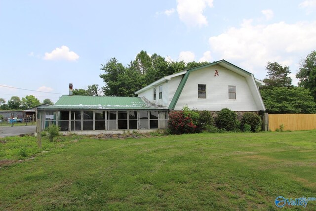 rear view of property with a sunroom and a lawn