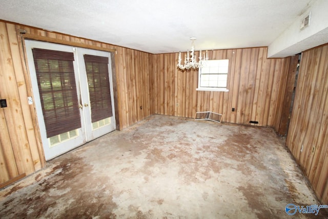 unfurnished dining area with wooden walls, visible vents, and a textured ceiling