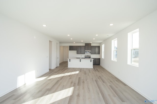 unfurnished living room featuring sink and light hardwood / wood-style flooring