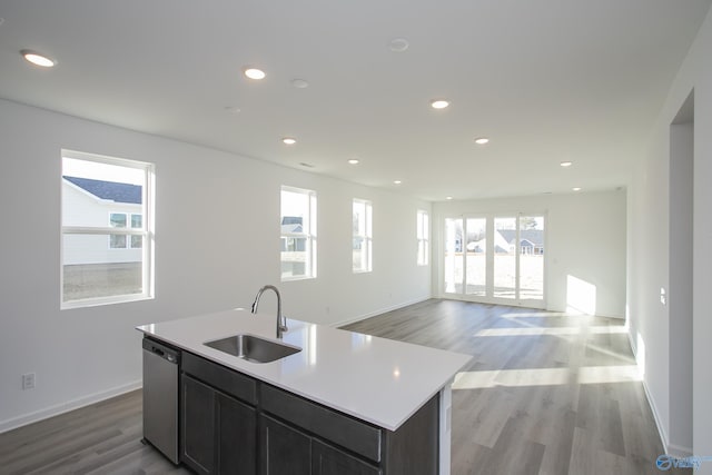 kitchen with an island with sink, sink, stainless steel dishwasher, and light hardwood / wood-style flooring