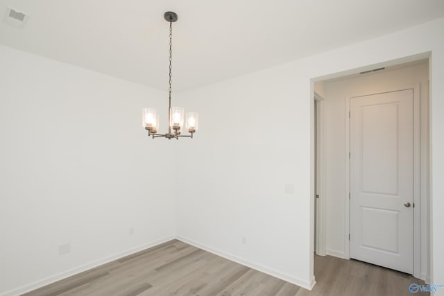 unfurnished room featuring a notable chandelier and light hardwood / wood-style floors