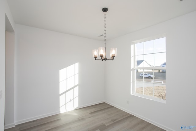 spare room with wood-type flooring and a chandelier