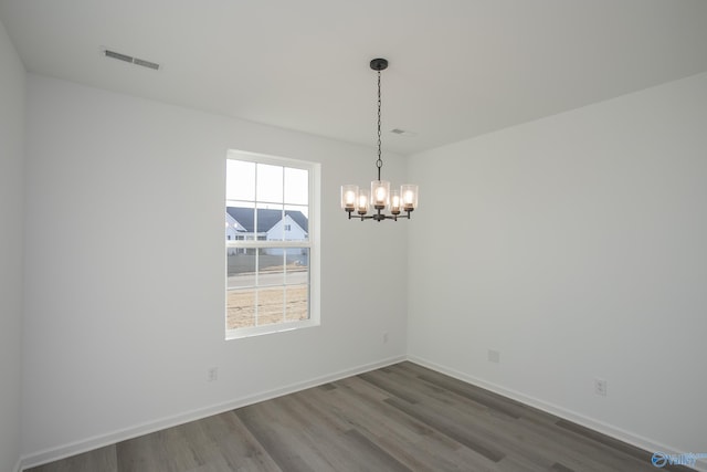 spare room featuring hardwood / wood-style flooring and a notable chandelier