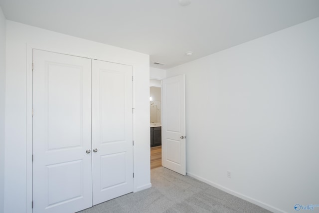 unfurnished bedroom with light carpet and a closet