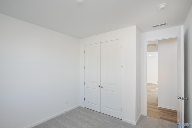 unfurnished bedroom featuring light colored carpet and a closet