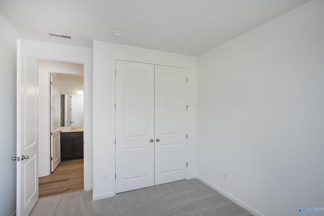 unfurnished bedroom with light colored carpet and a closet