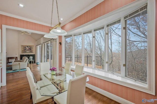 dining room with crown molding, lofted ceiling, plenty of natural light, and hardwood / wood-style flooring