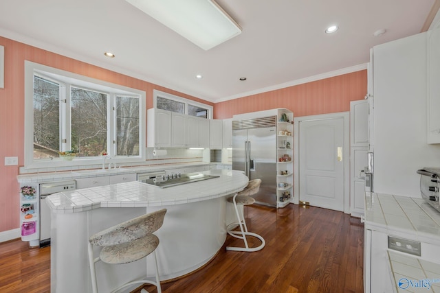 kitchen with sink, white cabinetry, tile countertops, a kitchen breakfast bar, and stainless steel appliances