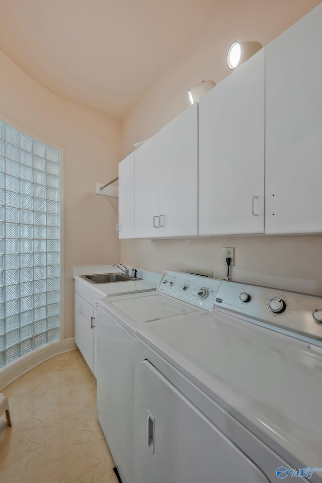 washroom with sink, washing machine and dryer, and cabinets