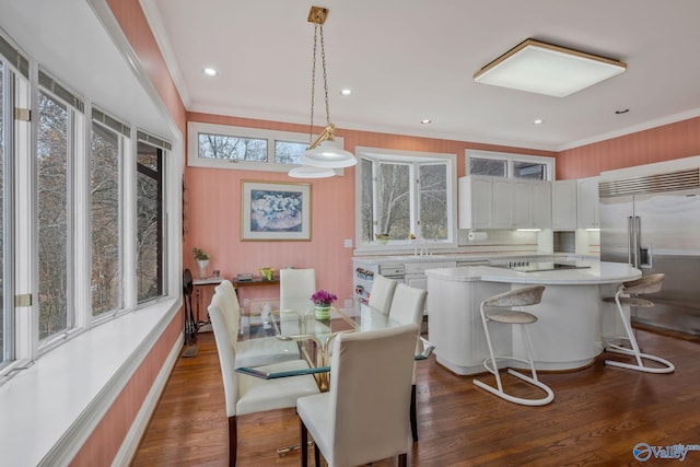 dining area with dark wood-type flooring, ornamental molding, and a wealth of natural light