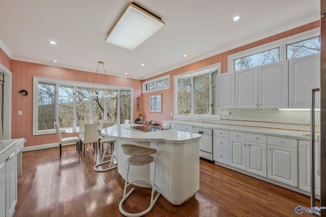 kitchen featuring white dishwasher, hanging light fixtures, a center island, and white cabinets