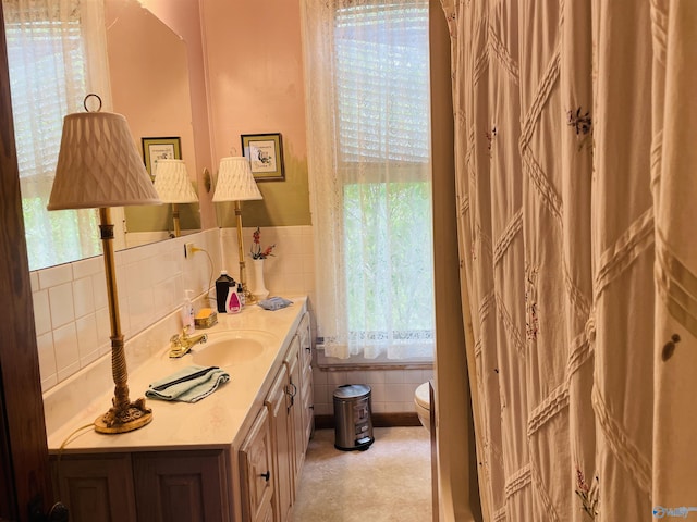 bathroom with vanity, toilet, and tile walls