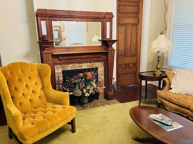 sitting room with a tile fireplace and carpet flooring