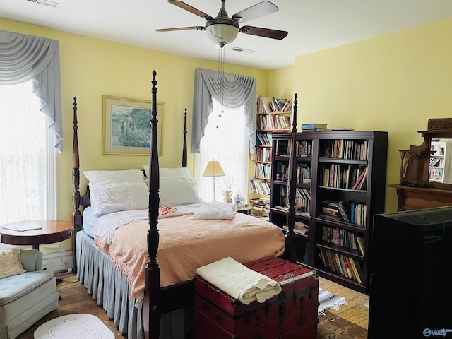 bedroom with ceiling fan, wood-type flooring, and multiple windows