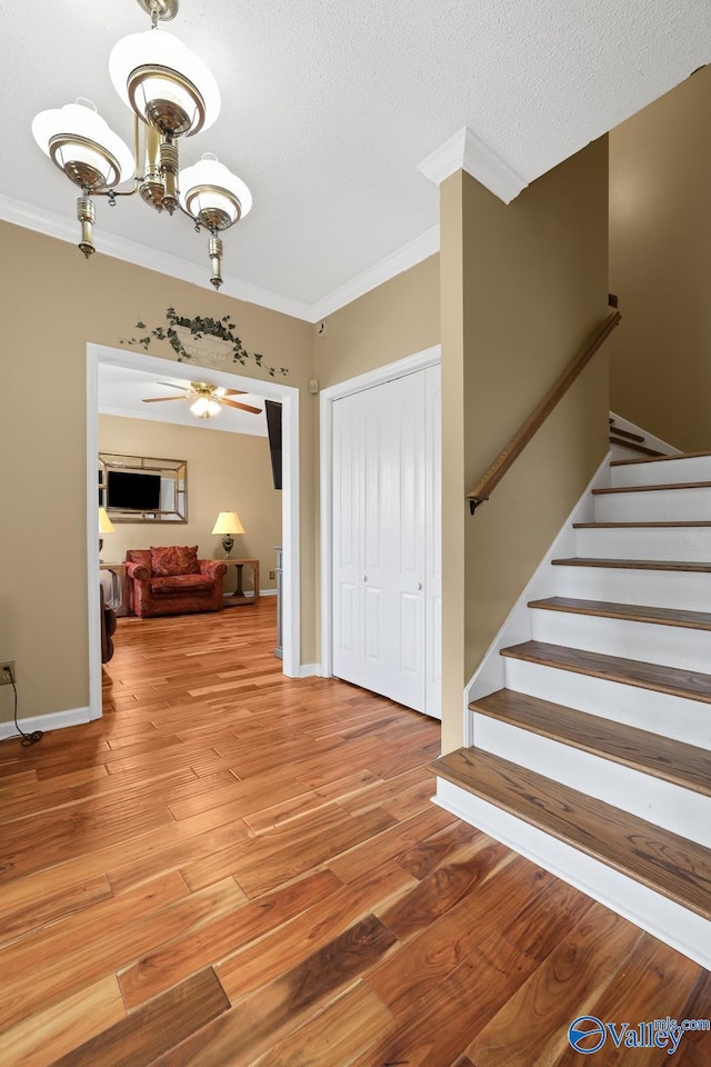 foyer entrance featuring hardwood / wood-style flooring, ornamental molding, a textured ceiling, and a notable chandelier