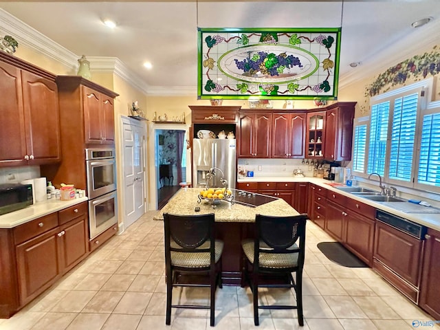 kitchen featuring appliances with stainless steel finishes, light tile patterned flooring, a breakfast bar area, crown molding, and a kitchen island with sink