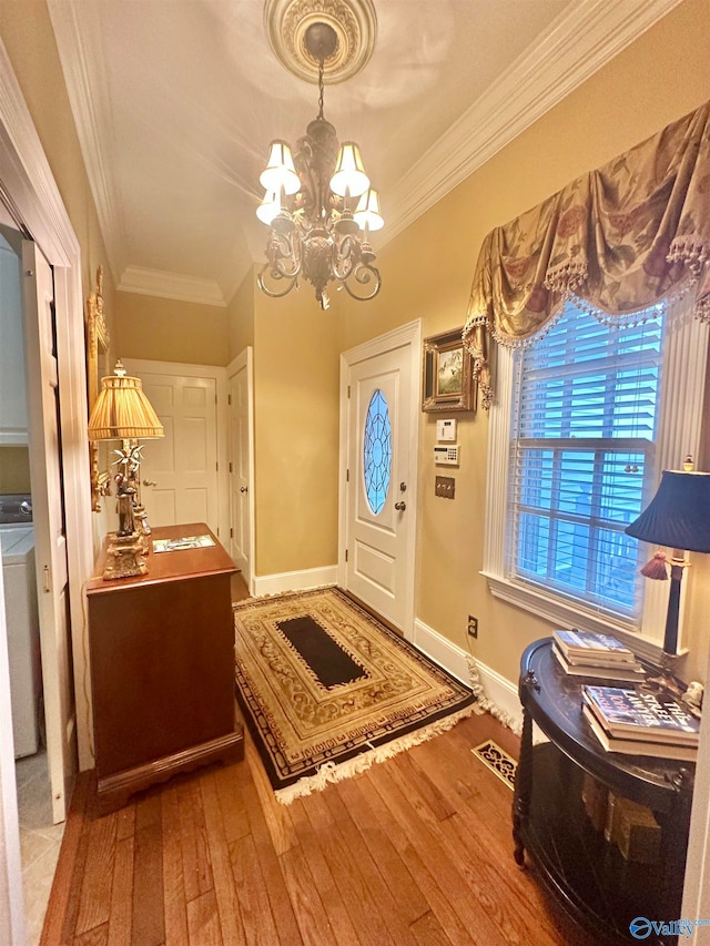 foyer with an inviting chandelier, crown molding, washer / clothes dryer, and hardwood / wood-style floors