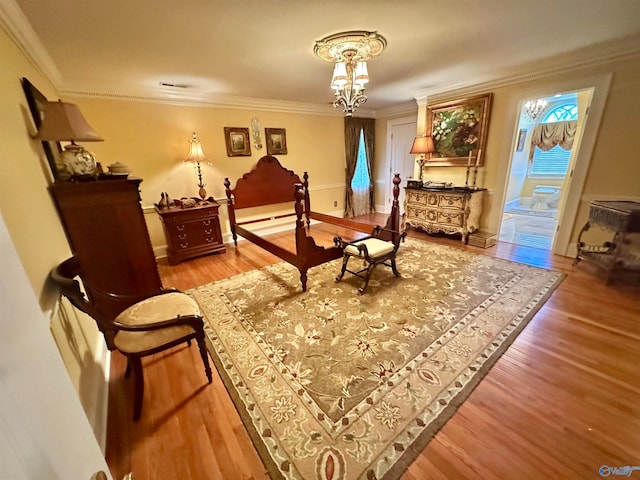 bedroom featuring connected bathroom, an inviting chandelier, crown molding, and hardwood / wood-style floors