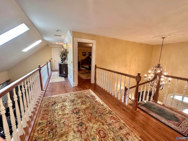 hall featuring an inviting chandelier, hardwood / wood-style flooring, and lofted ceiling with skylight