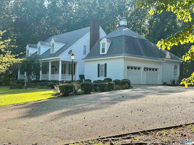 cape cod-style house featuring covered porch, a front yard, and a garage