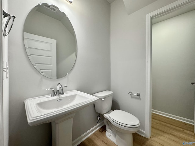 half bath featuring baseboards, toilet, and wood finished floors