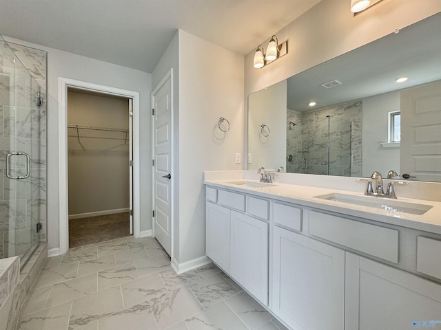 bathroom with a spacious closet, marble finish floor, a marble finish shower, and a sink