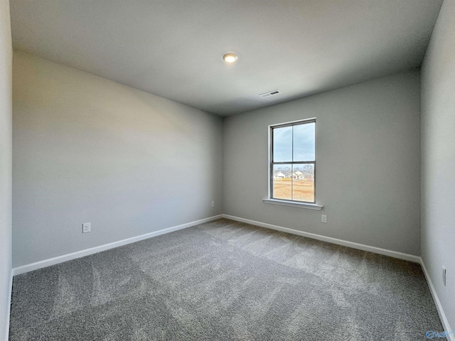 carpeted spare room with visible vents and baseboards