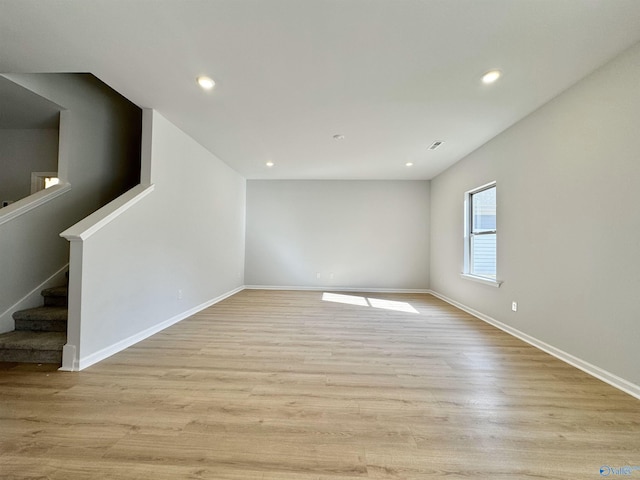 empty room with light wood-type flooring, stairway, baseboards, and recessed lighting