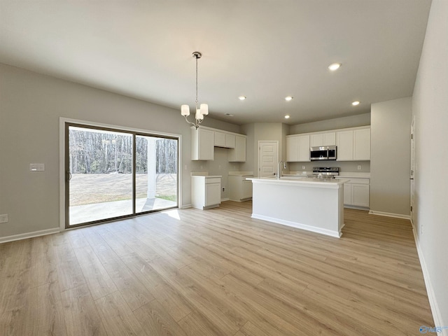 kitchen with recessed lighting, appliances with stainless steel finishes, white cabinets, and light wood finished floors