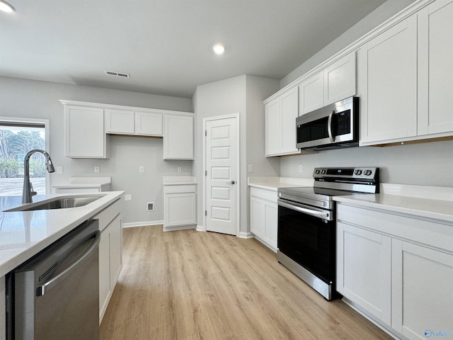 kitchen featuring visible vents, a sink, white cabinetry, appliances with stainless steel finishes, and light countertops