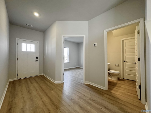 foyer entrance featuring wood finished floors, visible vents, and baseboards