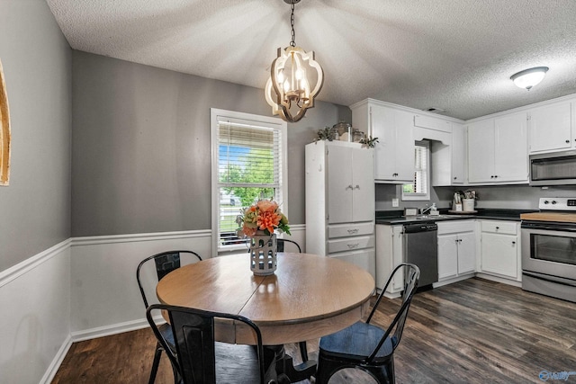 982 Bell Factory Rd, Huntsville, AL 35811 - kitchen with a chandelier, dark countertops, a textured ceiling, appliances with stainless steel finishes, and dark wood finished floors
