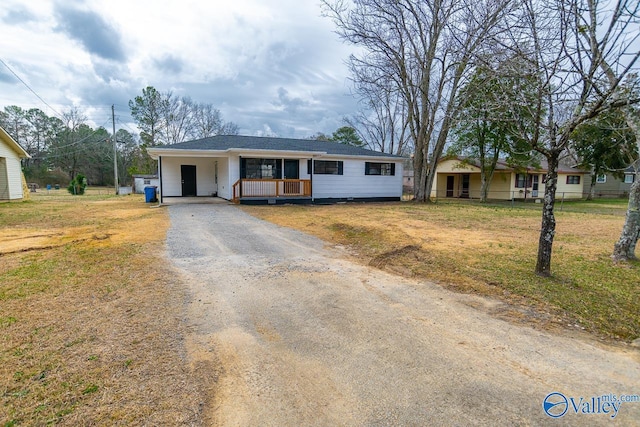 ranch-style home featuring a carport, covered porch, and a front lawn